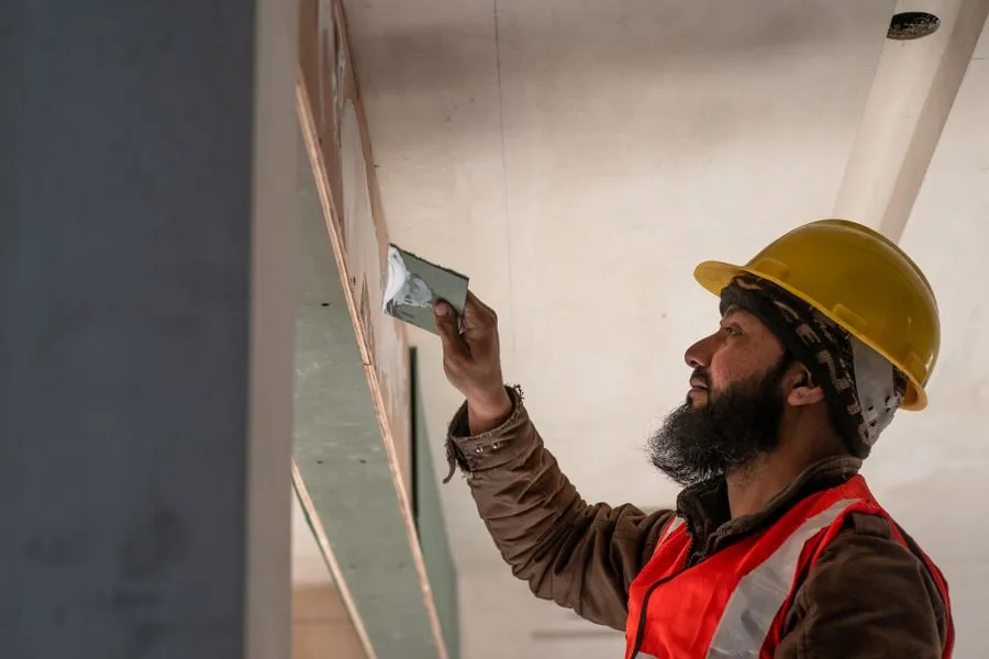 AS Home Solutions MD tradesman in a hard hat skimming a wall by hand on a Frederick, Maryland job